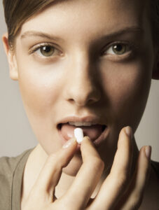 Young woman taking medicine, portrait, close-up