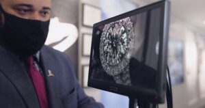 Jewelry consultant examines a diamond on a computer screen.